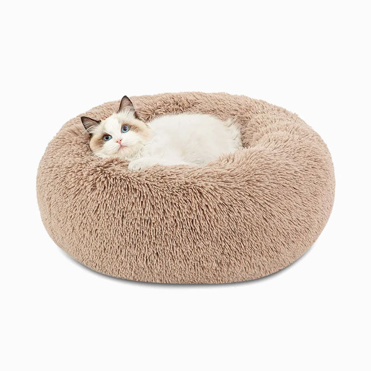 Cat relaxing in a beige faux-fur donut bed